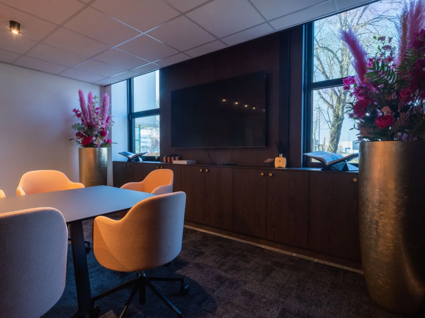 Vergaderzaal met ovale tafel, oranje stoelen en daglicht via de ramen in Office Capital Maastricht-Airport