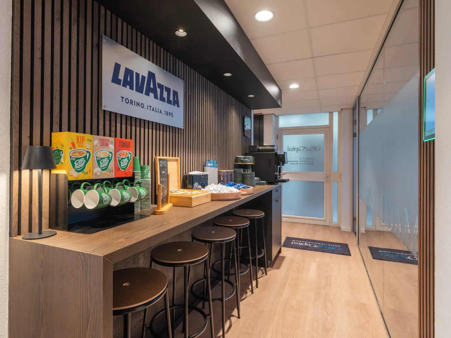 Lavazza koffiecorner met barkrukken, koffiemachine en thee in Office Capital Maastricht-Airport