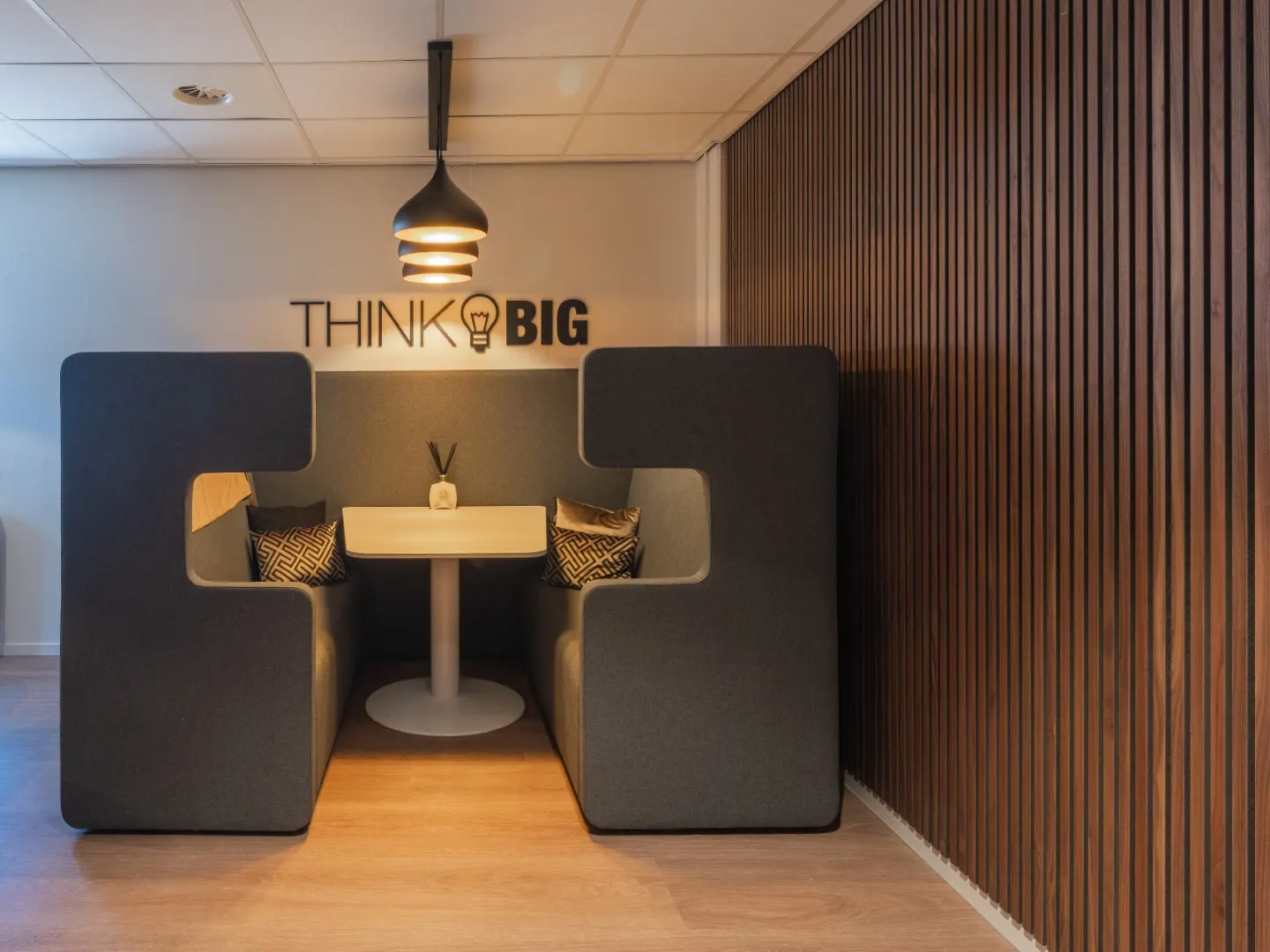 Afgeschermde overlegbooth met zithoek en de muurtekst Think Big in Office Capital Maastricht-Airport