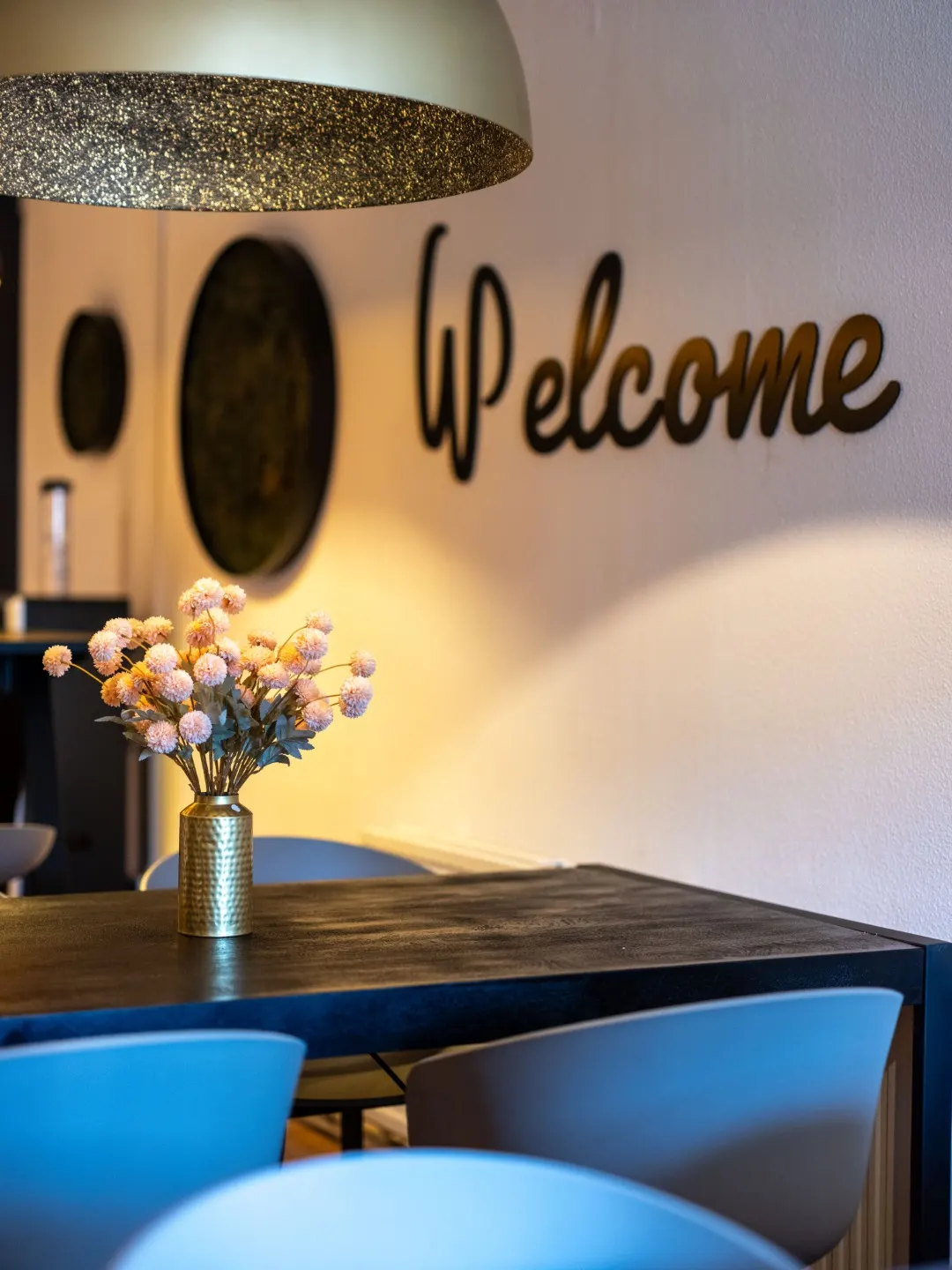 Eethoek met blauwe stoelen onder de muurtekst Welcome in Office Capital Maastricht-Airport