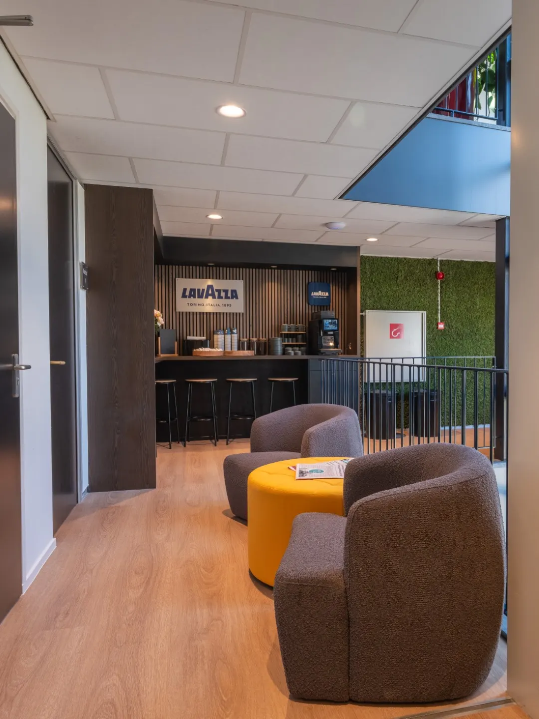 Doorkijk naar de loungeruimte met fauteuils in Office Capital Maastricht-Airport
